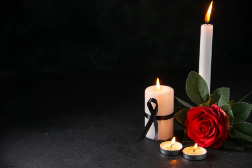 front-view-burning-candle-with-red-flower-dark-surface